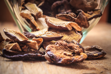 Dry mushrooms in jar on wooden table.