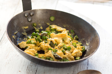 Green asparagus with egg in a frying pan.