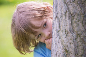 Little boy playing hide and seek in the park