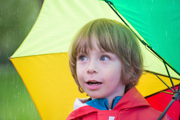 Little boy with umbrella in the rain