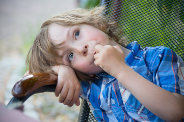 Little boy relaxing in the armchair outside