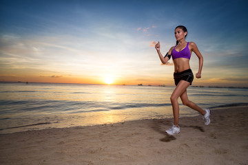 Sport woman running on the beach at sunrise