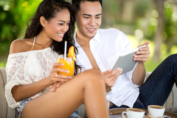 young couple in beach bar using tablet