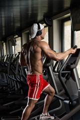 Fototapeta na wymiar Mature Man Doing Aerobics Elliptical Walker In Gym