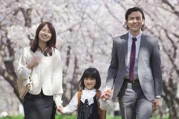 桜並木を歩く家族