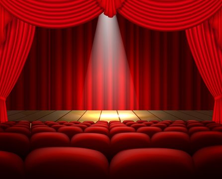 A theater stage with a red curtain, seats and a spotlight