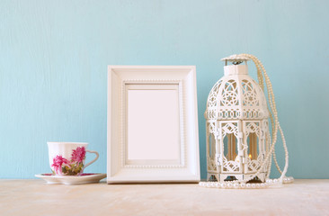 vintage classical white frame on wooden table with lantern
