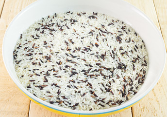 Rice brown in a ceramic bowl with wooden background.