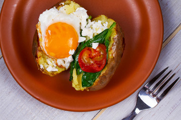 Baked potato with fried egg, feta, spinach and tomato cherry