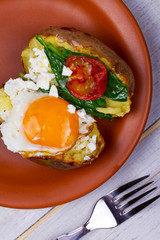 Baked potato with fried egg, feta, spinach and tomato cherry