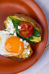 Baked potato with fried egg, feta, spinach and tomato cherry