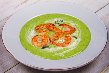 Green organic vegetable and creamy soup with shrimps