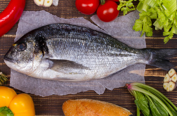 Delicious fresh fish and vegetables on dark vintage background