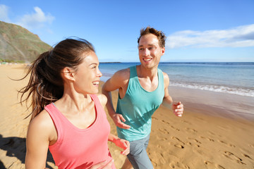 Young couple talking running on beach jogging