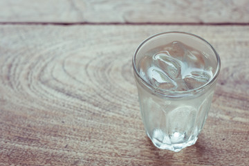 Drinking water with ice in glass on wooden table