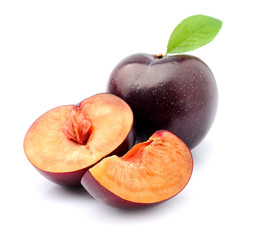 Ripe plums with leaves close up on white background.