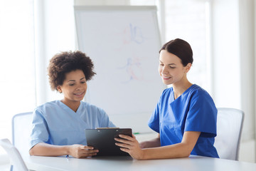 happy doctors with tablet pc meeting at hospital