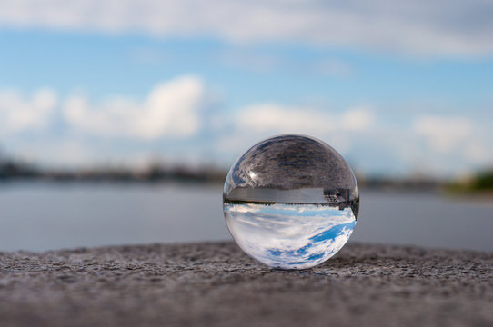 Glass transparent ball on river background and grainy surface