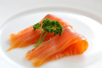 Salmon slices with parsley on a white plate