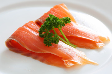 Salmon slices with parsley on a white plate.