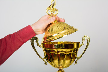 Hand opens lid of gold cup