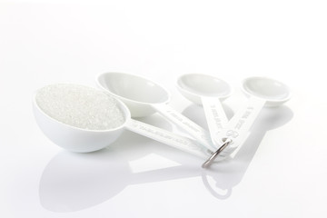 Sugar in measuring spoons on white background
