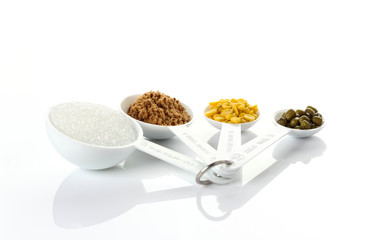 Beans in measuring spoons on white background