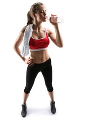 Beautiful young woman drinking water after training