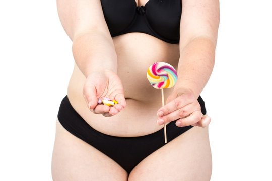 Woman showing her fat body and holding a lollipop and tablets. Healthy lifestyles concept and diet.
Obese neglected body isolated over white background.
