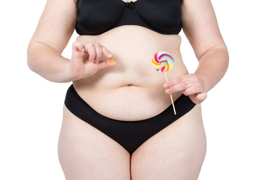 Woman showing her fat body and holding a lollipop and tablets. Healthy lifestyles concept and diet.
Obese neglected body isolated over white background.
