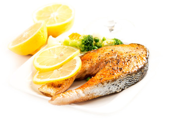 Grilled salmon and vegetables on plate with lemons