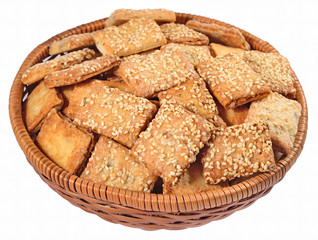 Cookies with sesame seeds in a wicker bowl on a white