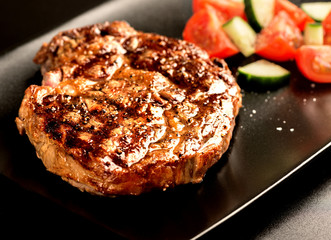 Grilled steak and vegetables on black plate