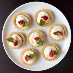 Many cakes with whipped cream, fresh fruits and mints
