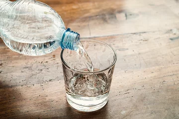 Foto auf Acrylglas blaue Wasserflasche in ein klares Glas gegossen © GianlucaCiroTancredi