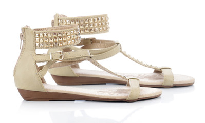 Beige sandals with studs on a white background  - obrazy, fototapety, plakaty