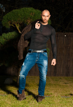 Attractive young man in a brown leather jacket pose in parck