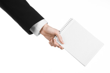 hand of a journalist in a black suit holding a notebook
