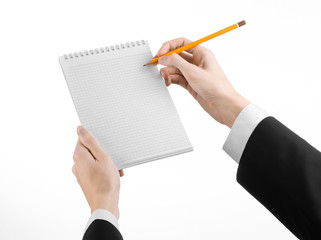 hand in a black suit holding a notebook with a pencil