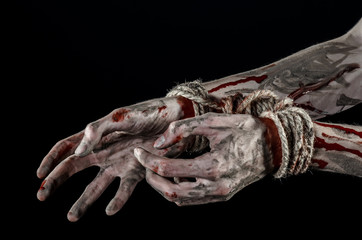 Hands bound,bloody hands, mud, rope, on a black background