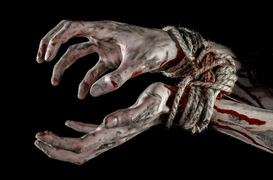 Hands bound,bloody hands, mud, rope, on a black background