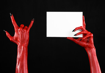 Red devil hand with black nails holding a blank white card