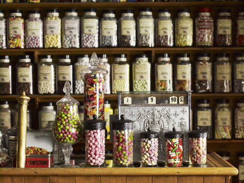 Traditional sweets displayed in tall glass jars on the shelves of a sweet shop. 