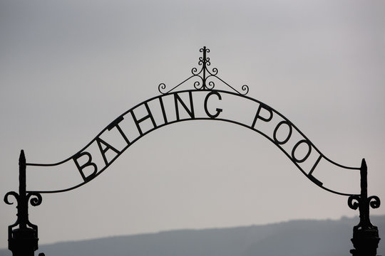 A metal arch over a gate to the Bathing Pool in a resort.