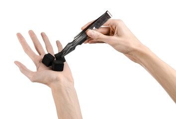 man holding a forceps with coal and puts them into a clay bowl