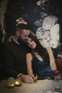 A couple sitting in a low lit bar, having a drink, relaxing.