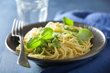 spaghetti pasta with pesto sauce over blue