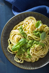 spaghetti pasta with pesto sauce over blue