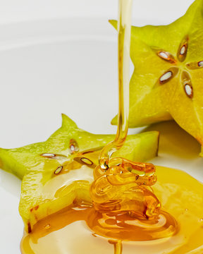 Studio shot of honey drizzling on slice of star fruit