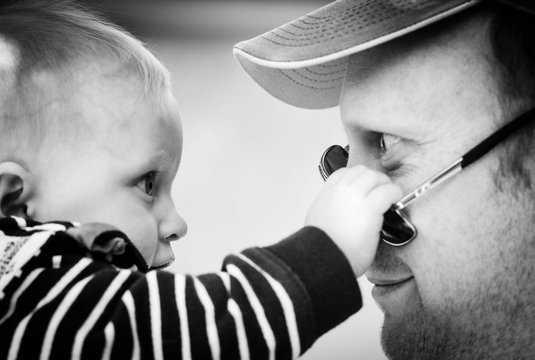 Australia, Canberra, Hackett, Baby boy (6-11 months)  playing with his father's sunglasses